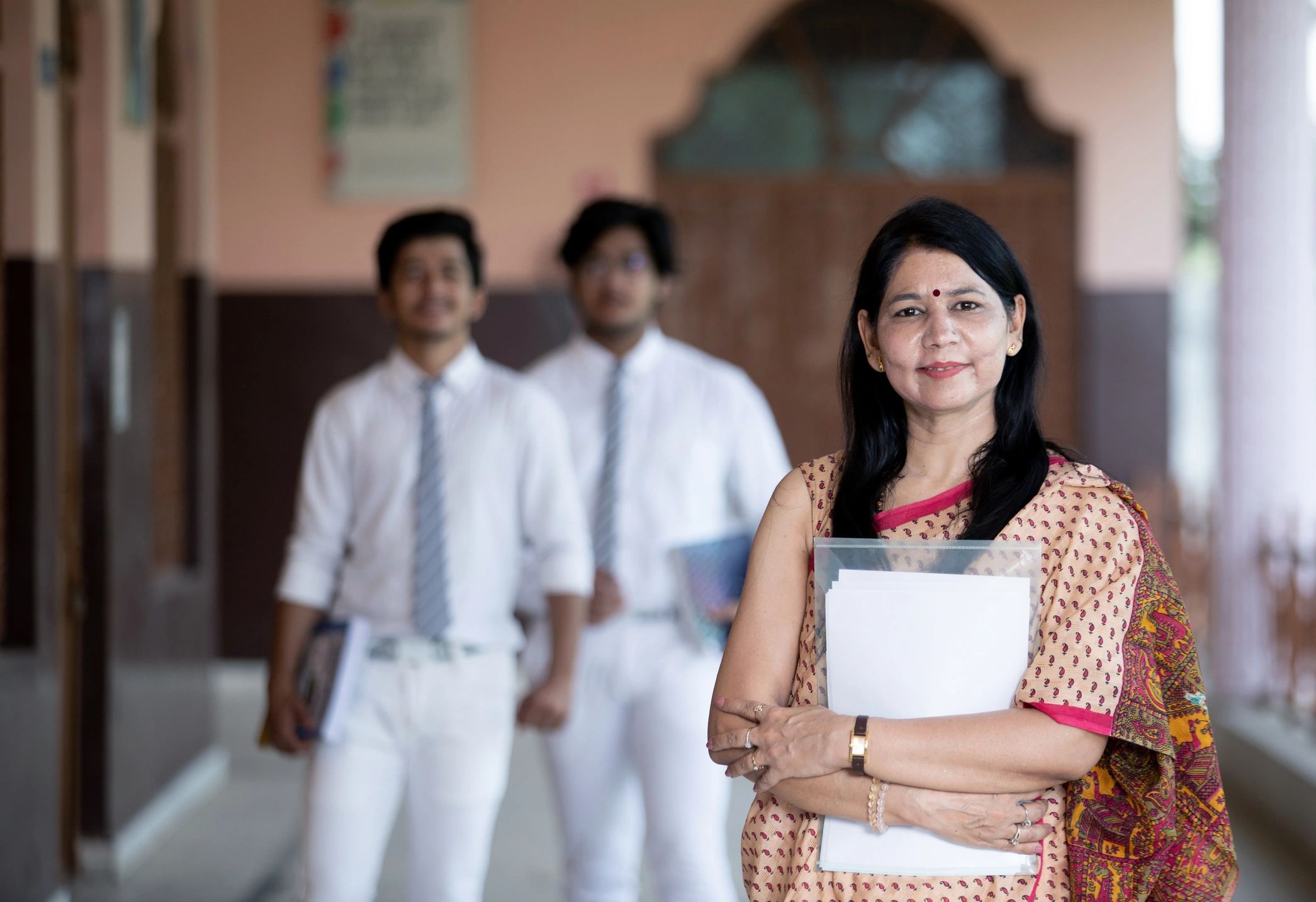Confident Indian school teacher with students in background