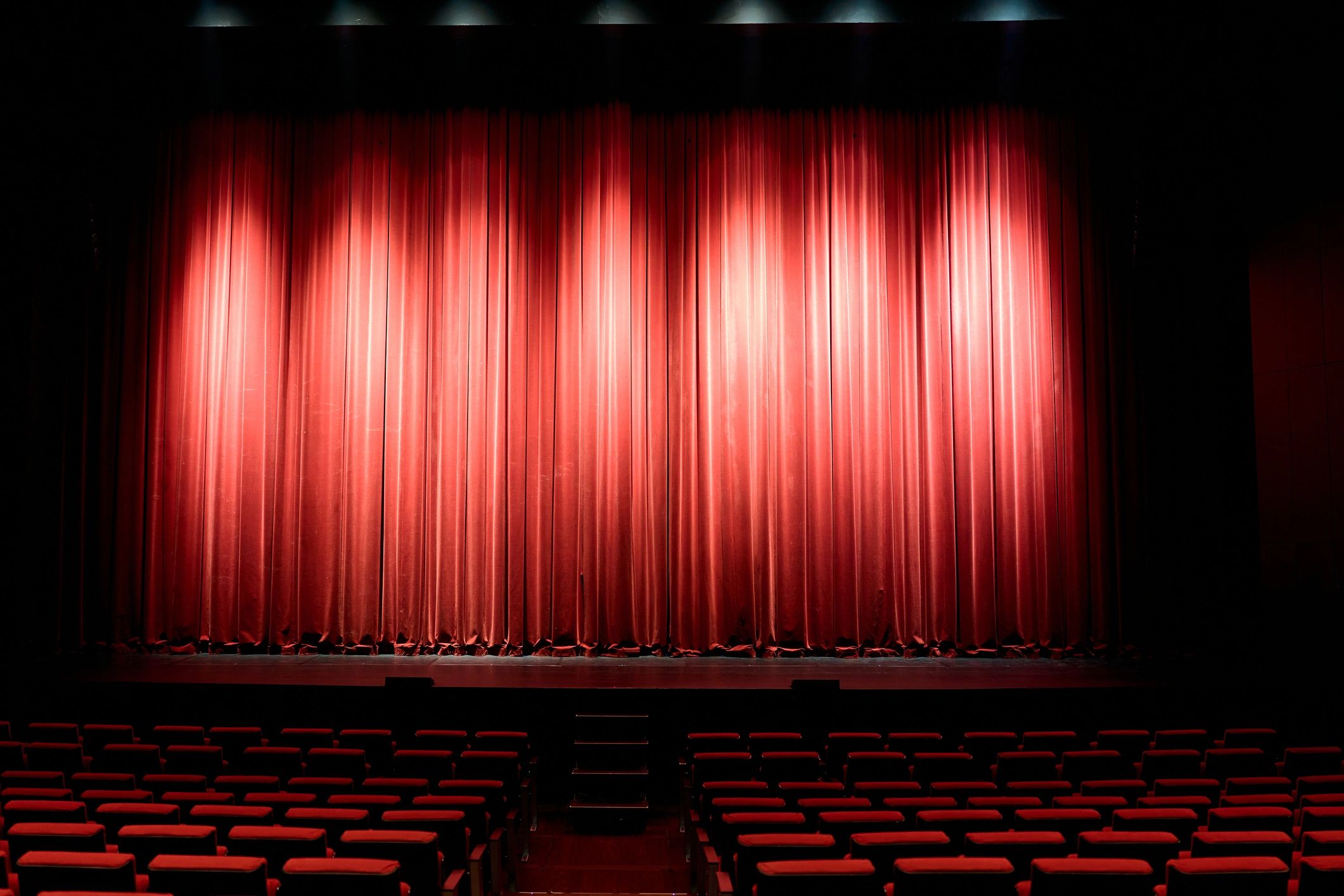 Red velvet curtain closing stage with theater seating